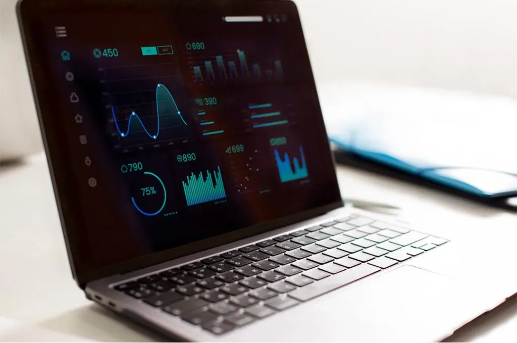 Ein Laptop auf einem Schreibtisch zeigt ein Dashboard mit verschiedenen Diagrammen und Statistiken auf dem Bildschirm